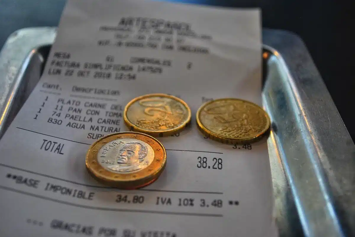 Close-up of anonymous hands placing a receipt and a printed invoice on a clean wooden desk next to a calculator