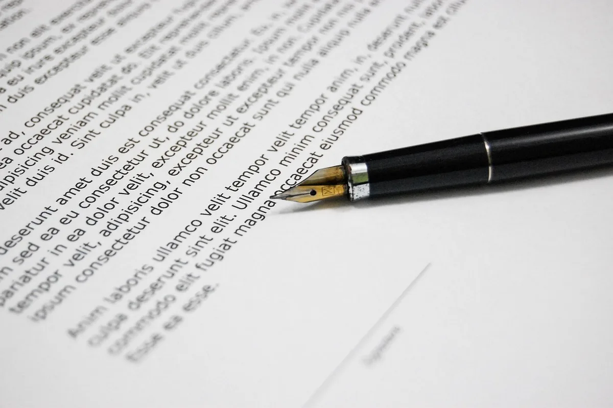 Hands filling out company formation documents on a bright desk, a printed statute page, and a smartphone nearby