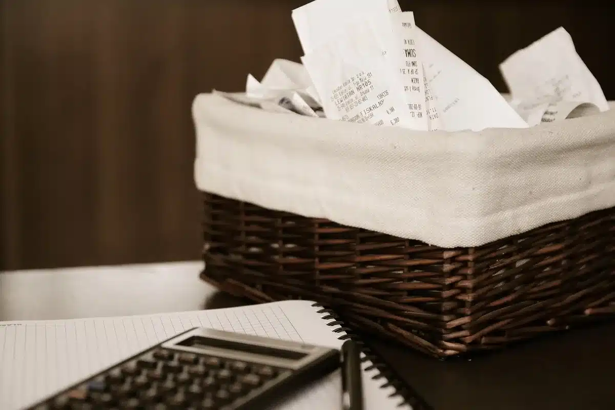 Close-up of a tidy desk with an open letter on plain paper titled Invoice reminder, a pen beside it, a calculator and a blurred coffee cup in the background