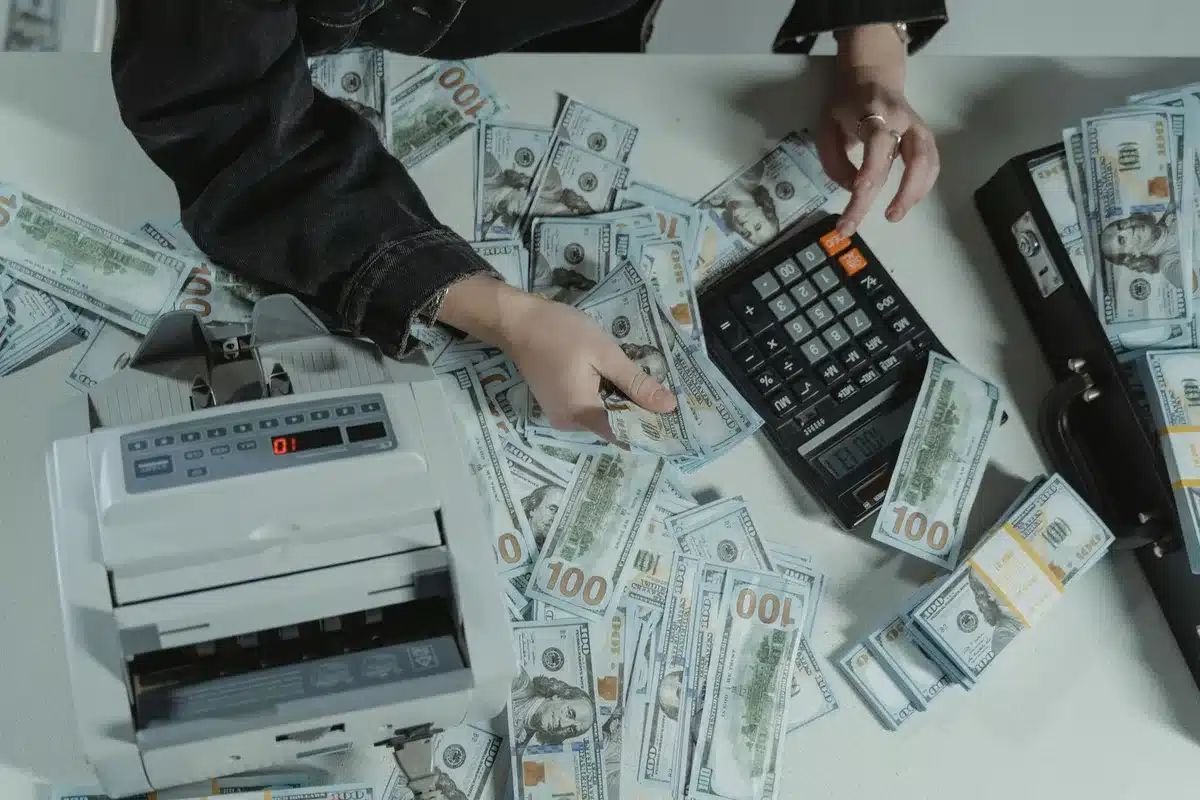 Desk with unopened business-plan folder, pen, and a calculator beside a laptop